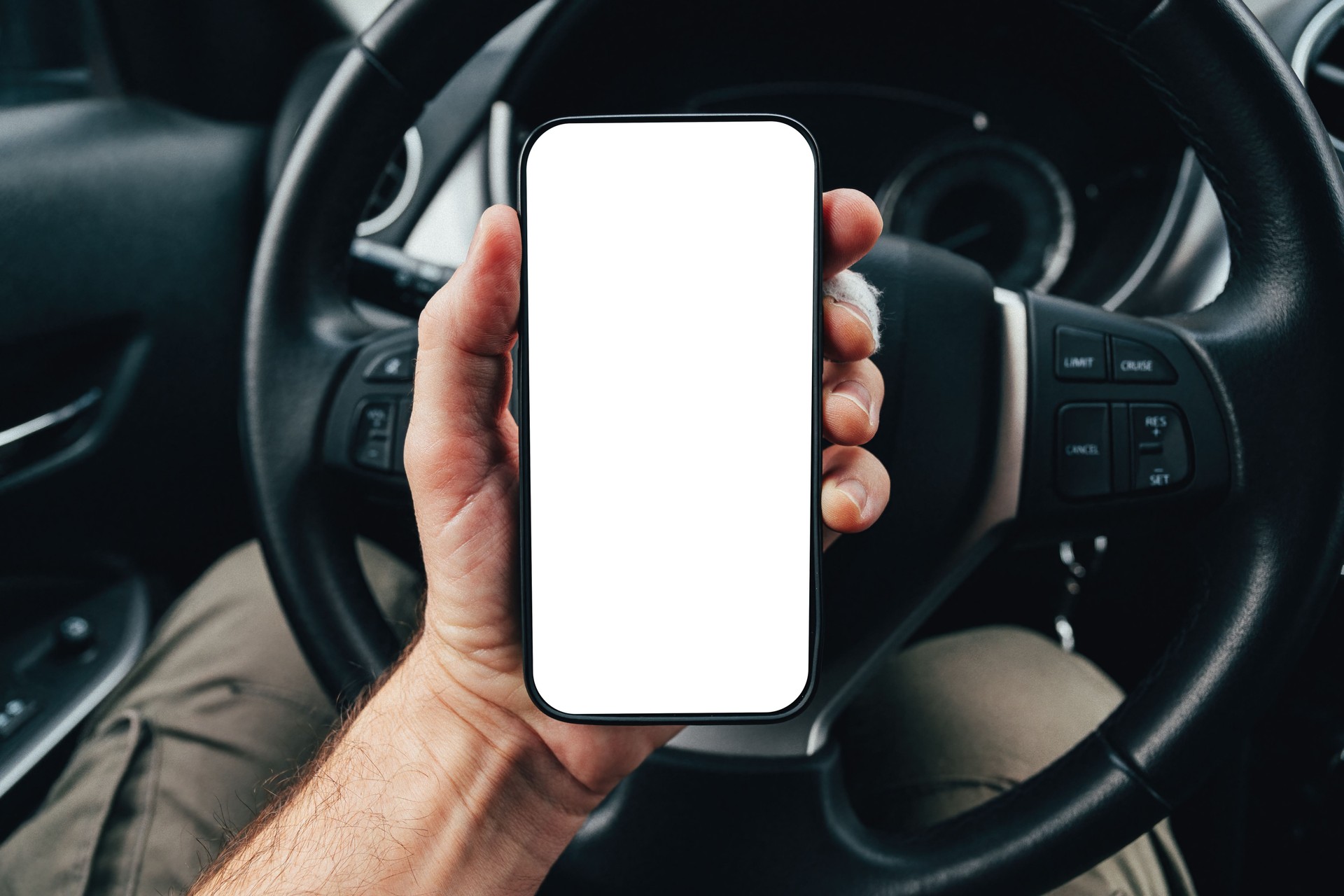 Driver app mockup with blank smartphone screen over steering wheel, man holding mobile phone device in car