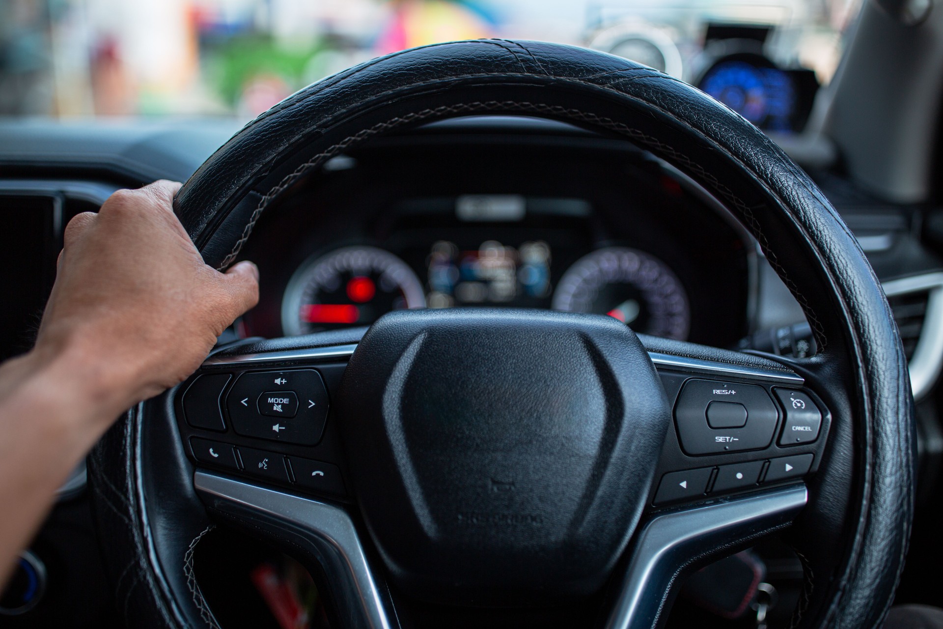 Car steering wheel and control buttons with human hands close up,Woman's hand presses the button on the steering wheel of the car close-up. Multi function buttons on steering wheel in car.